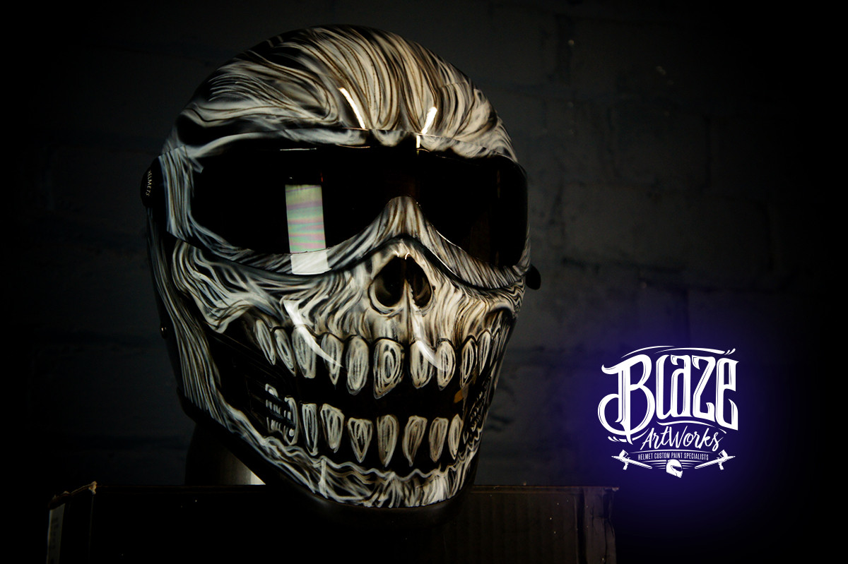 Gothic skull design motorcycle helmet with menacing fanged skull airbrush artwork in bone and black tones on dark background