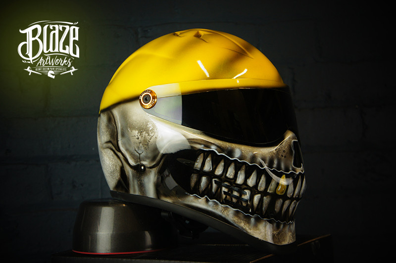 Yellow motorcycle helmet with detailed black and white grim reaper skull design featuring skeletal jaw and teeth detail