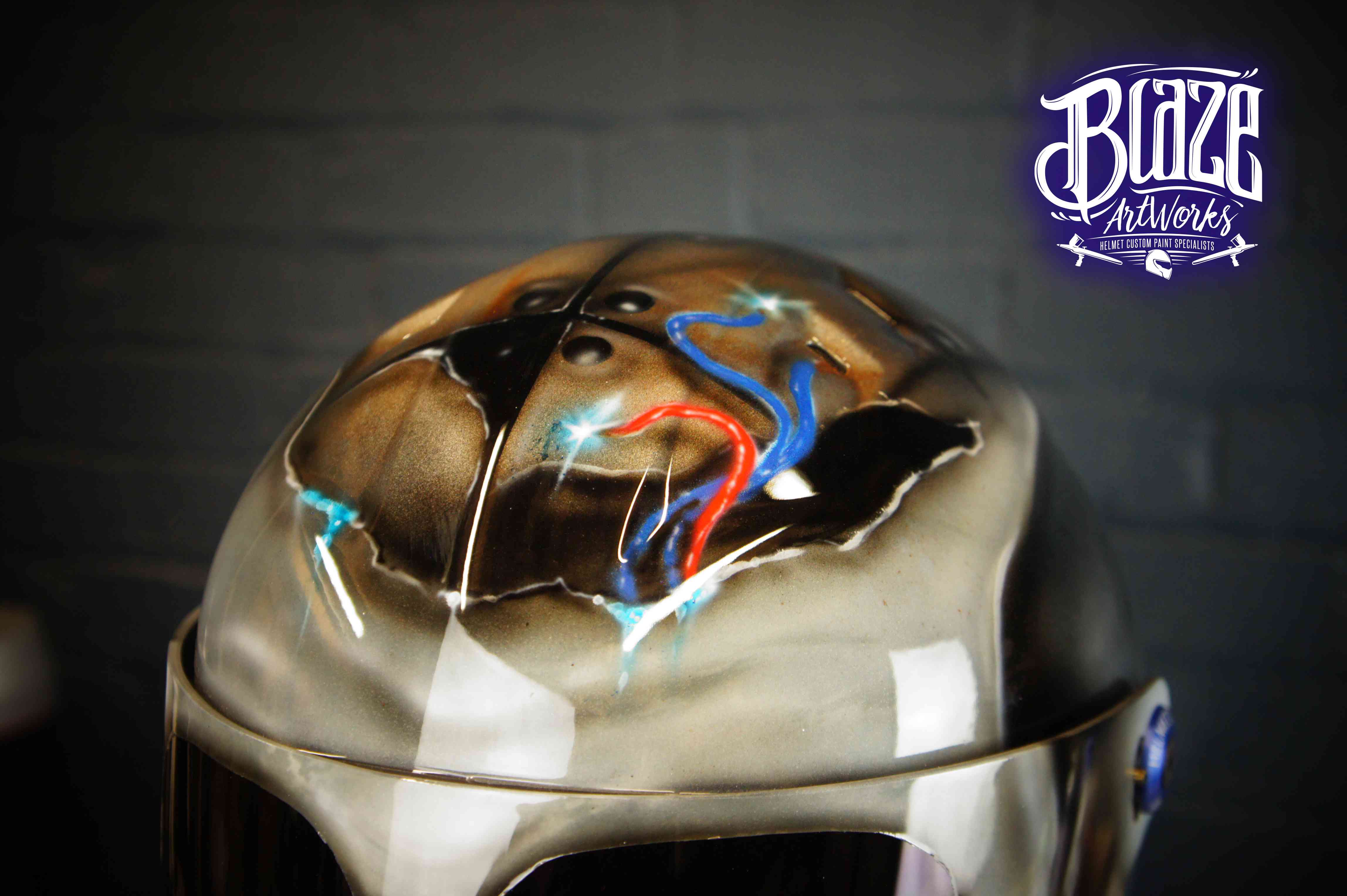 Chrome metallic motorcycle helmet with highly detailed airbrushed skull design featuring realistic bone structure in browns and blacks with blue and red accents