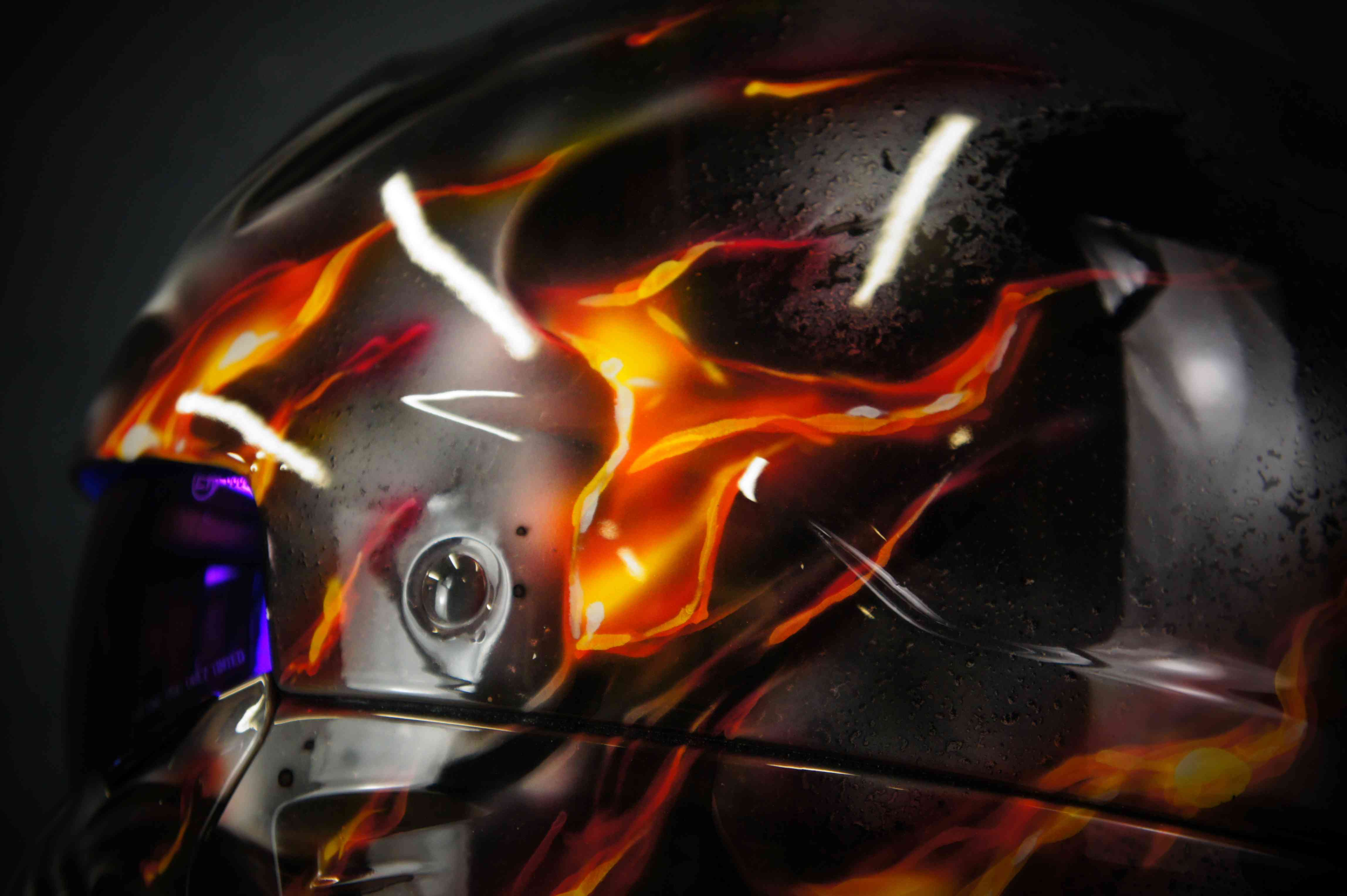 Black motorcycle helmet with realistic orange and red flames airbrushed across surface, dramatic fire effect artwork