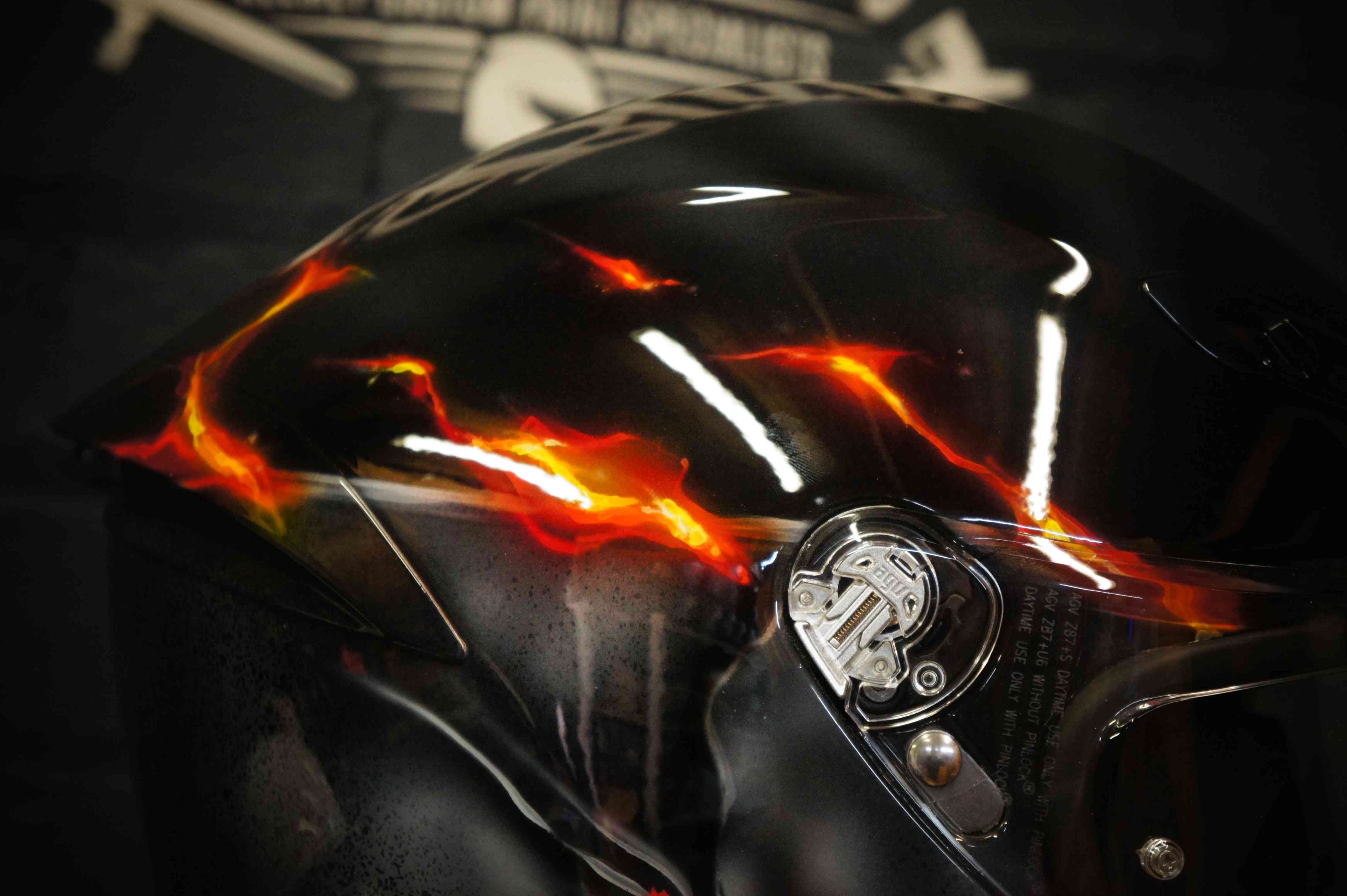 Black motorcycle helmet with realistic orange and red flames airbrushed across surface, creating dramatic fire effect