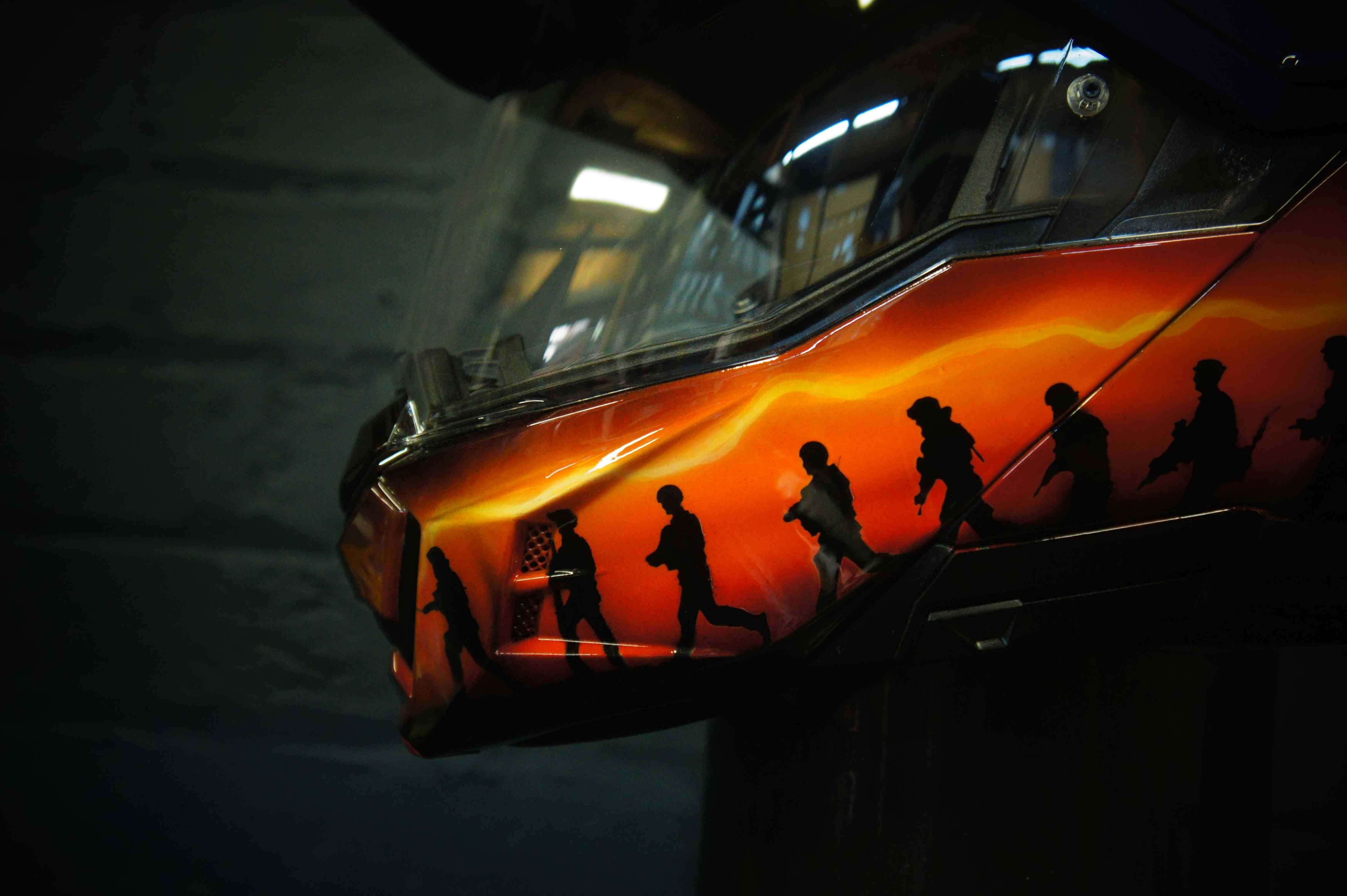 Motorcycle helmet with vibrant orange and yellow flame design airbrushed across black base, realistic fire effect paint job