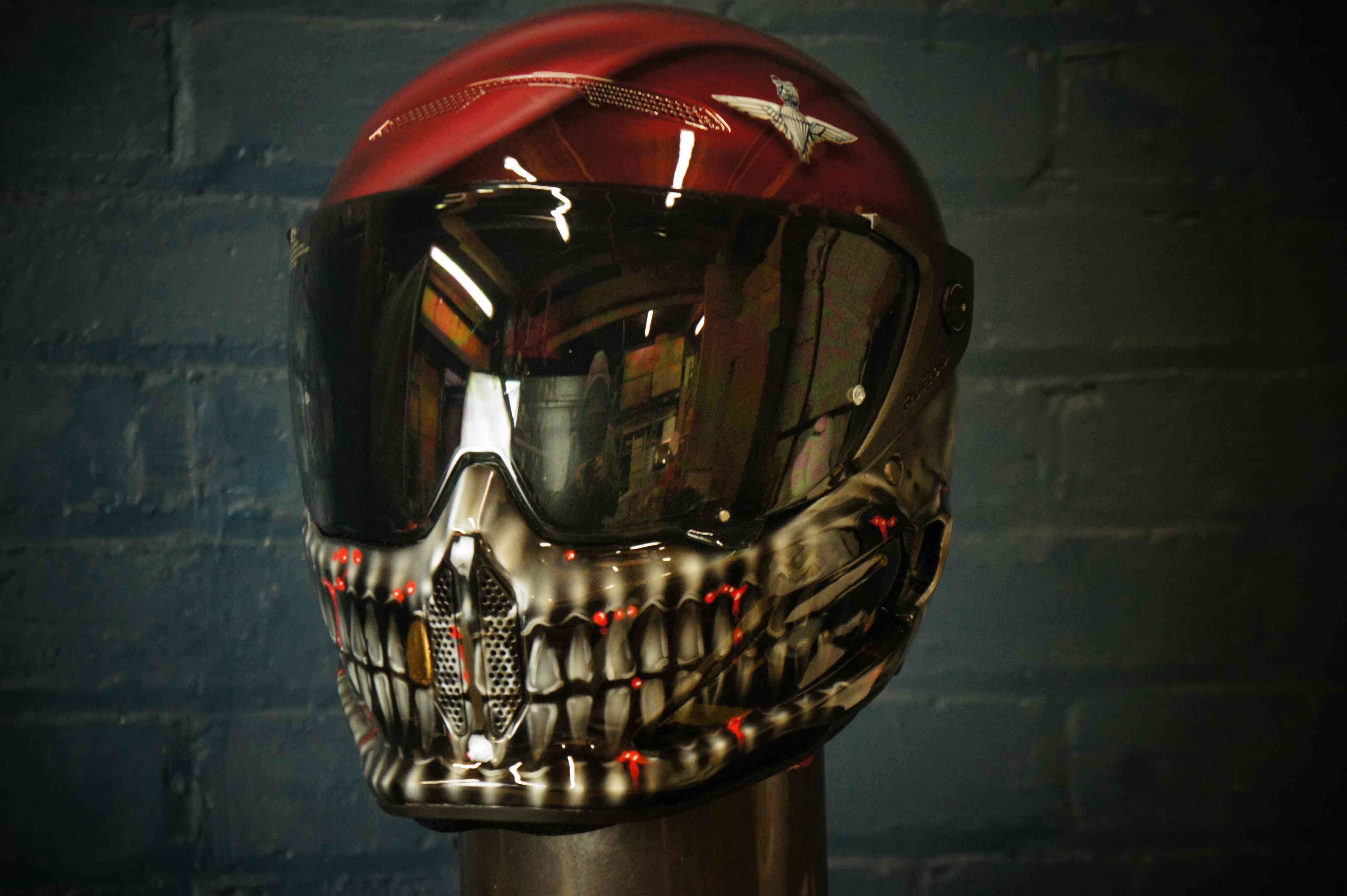 Red and black motorcycle helmet with detailed skeletal jaw design, white teeth, red LED accents, dark reflective visor