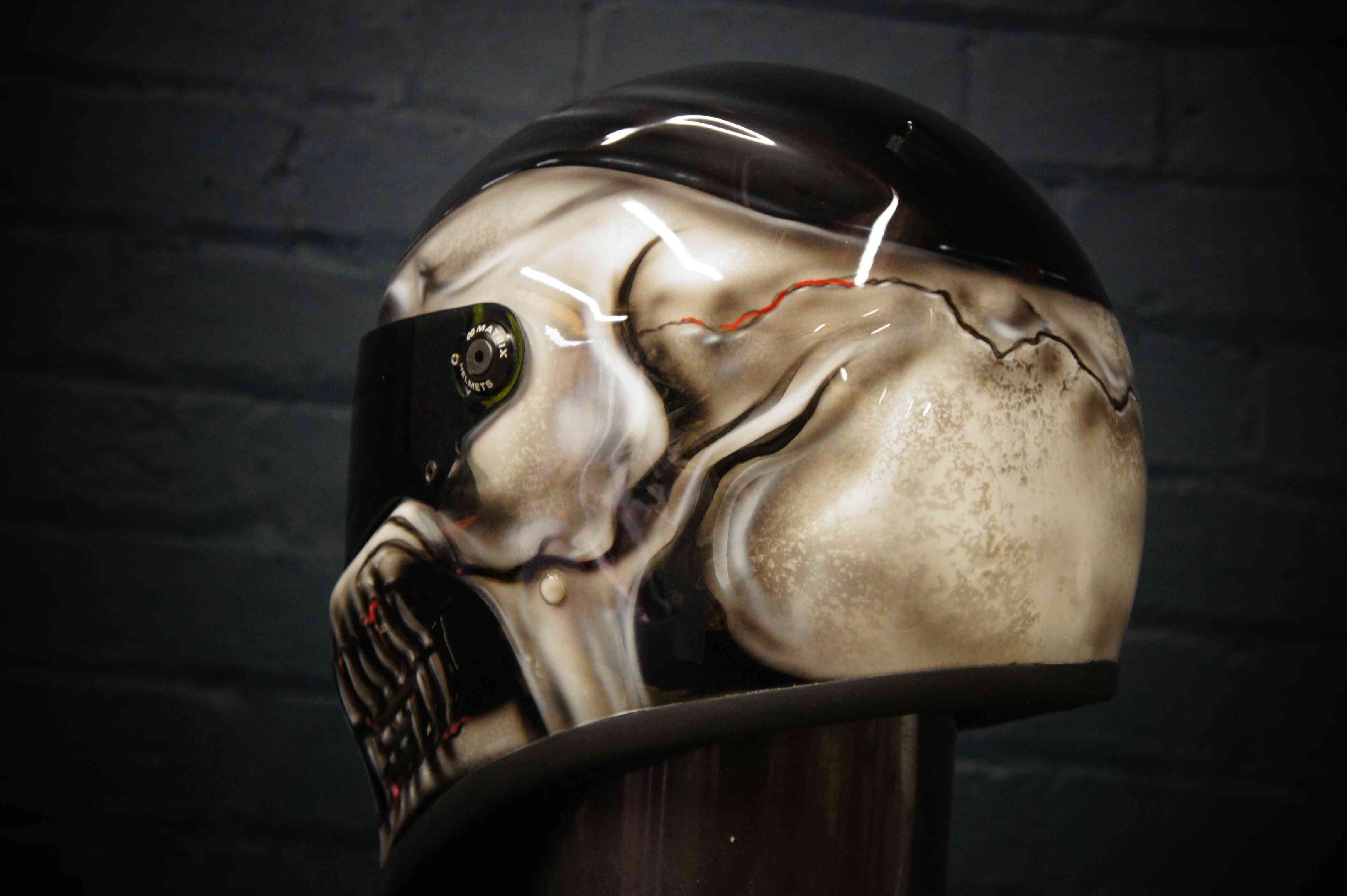 Black motorcycle helmet with highly detailed photorealistic grey skull design featuring anatomical bone structure and gothic horror elements