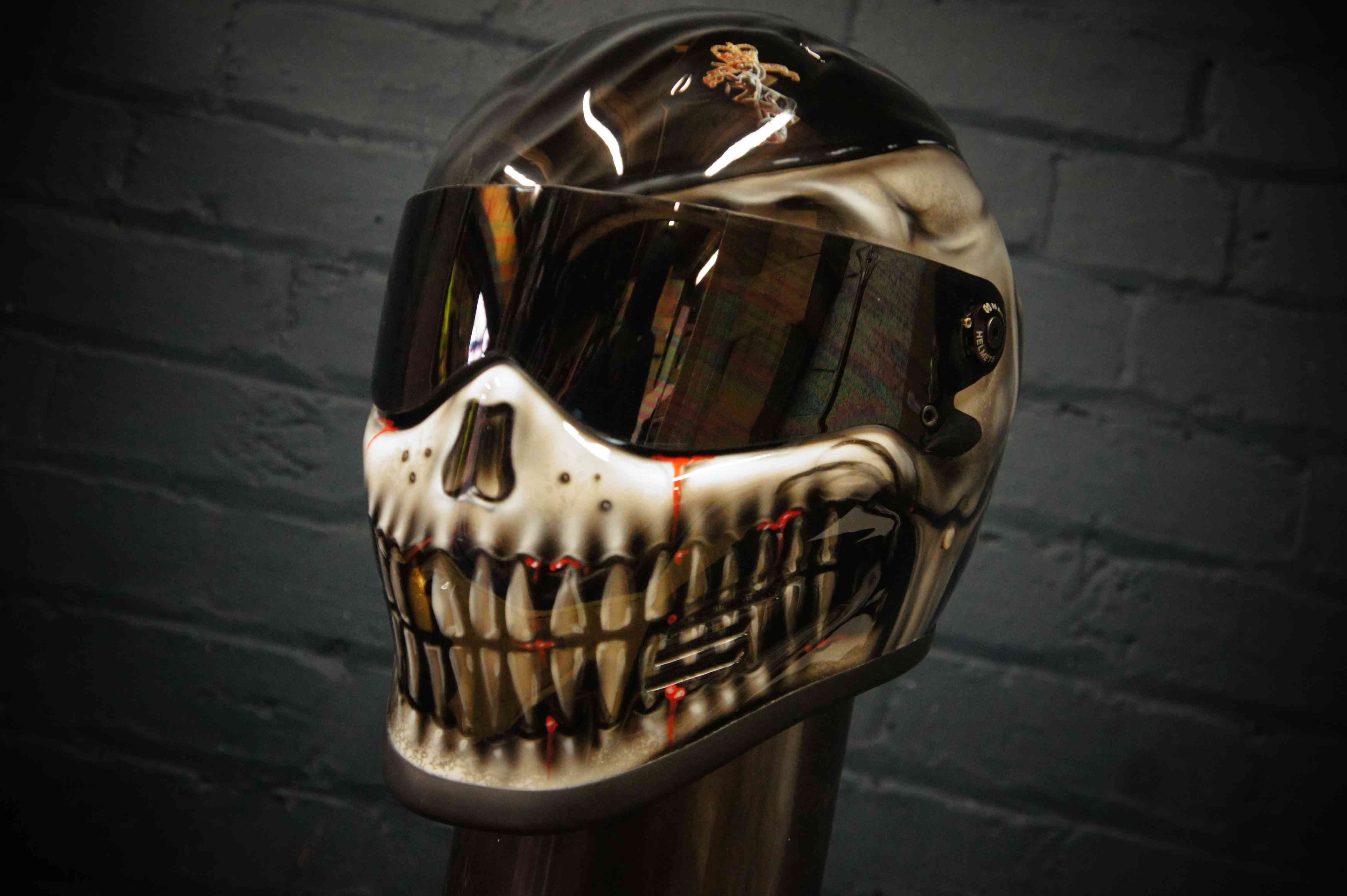 Black motorcycle helmet with realistic airbrrushed skull jaw design featuring white bone teeth, dark eye sockets and gothic horror styling