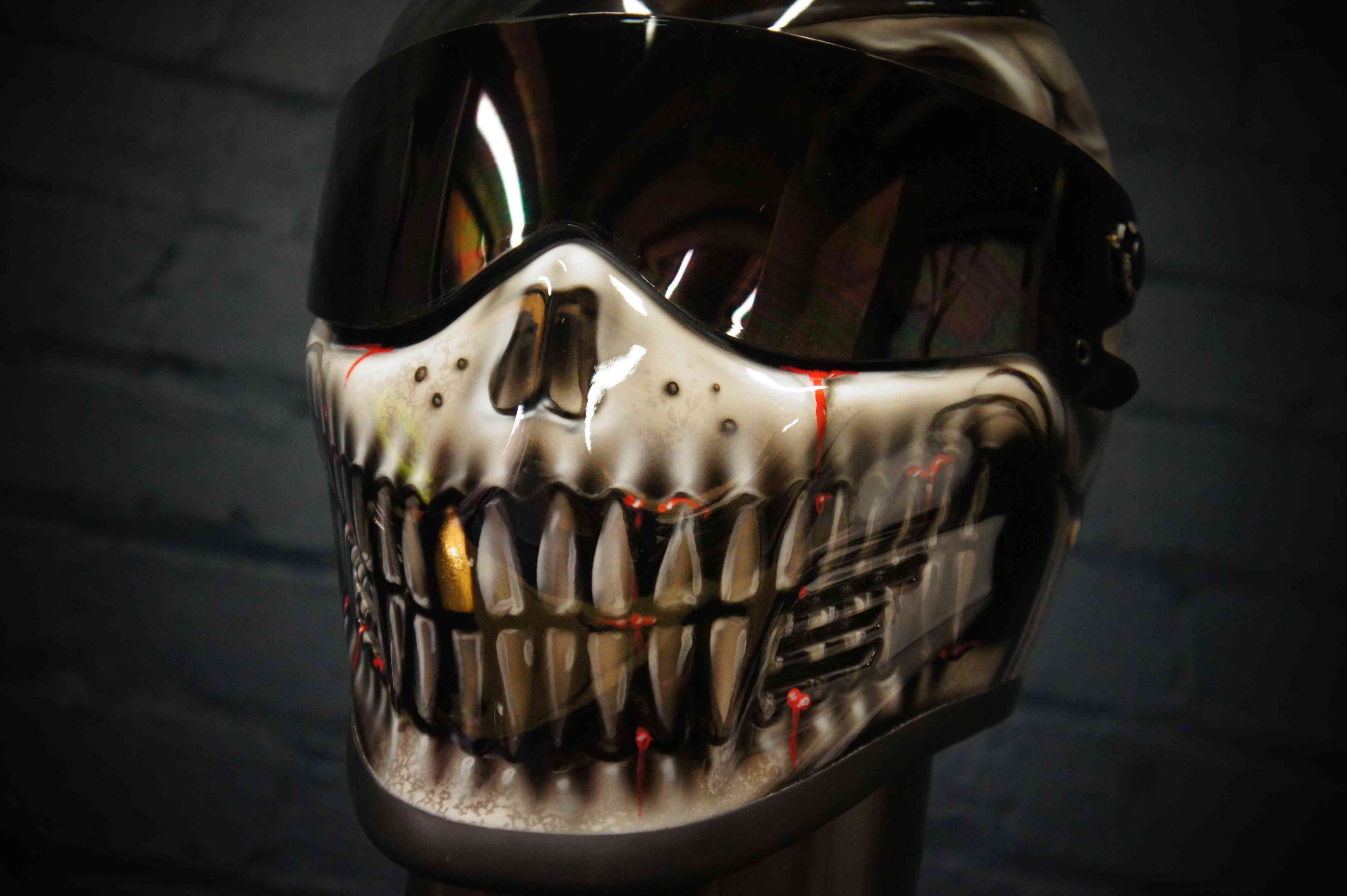White skull jaw design with bared teeth and red blood effects painted on motorcycle helmet with reflective visor