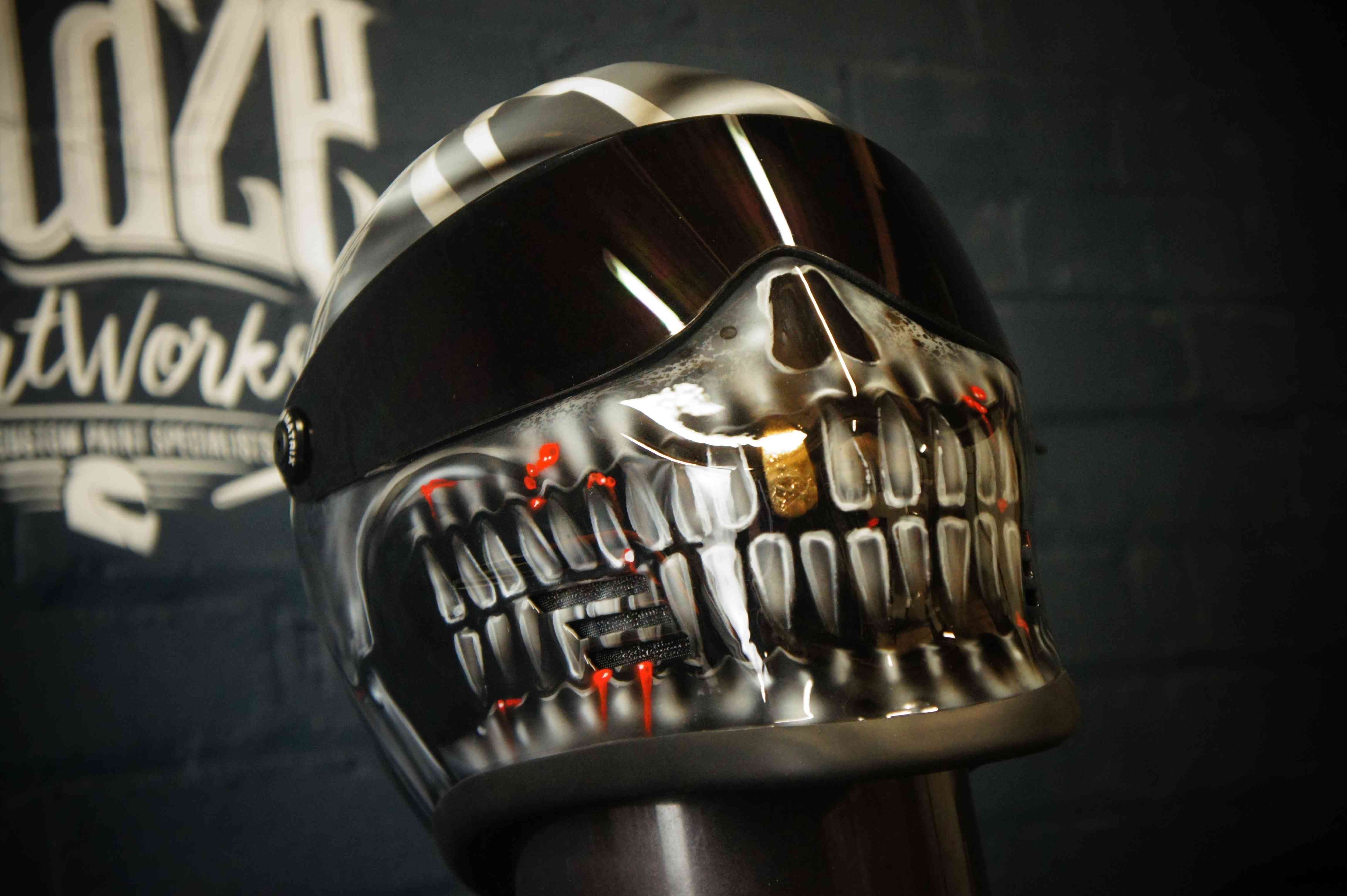Chrome metallic skull motorcycle helmet with glossy black visor, red LED accents, detailed teeth and jaw structure