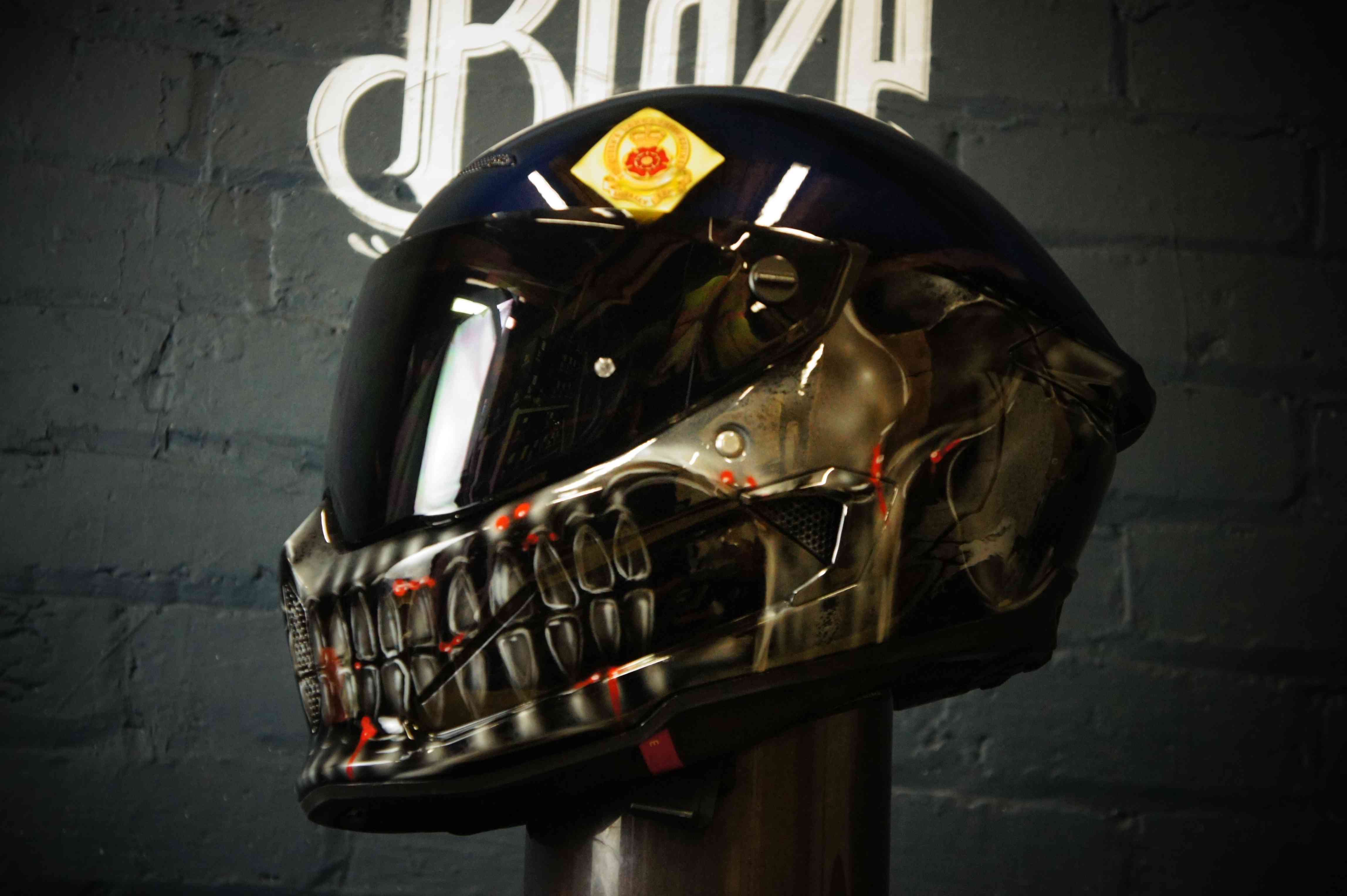 Black motorcycle helmet with metallic chrome skull face design featuring detailed bone structure and red accent lighting