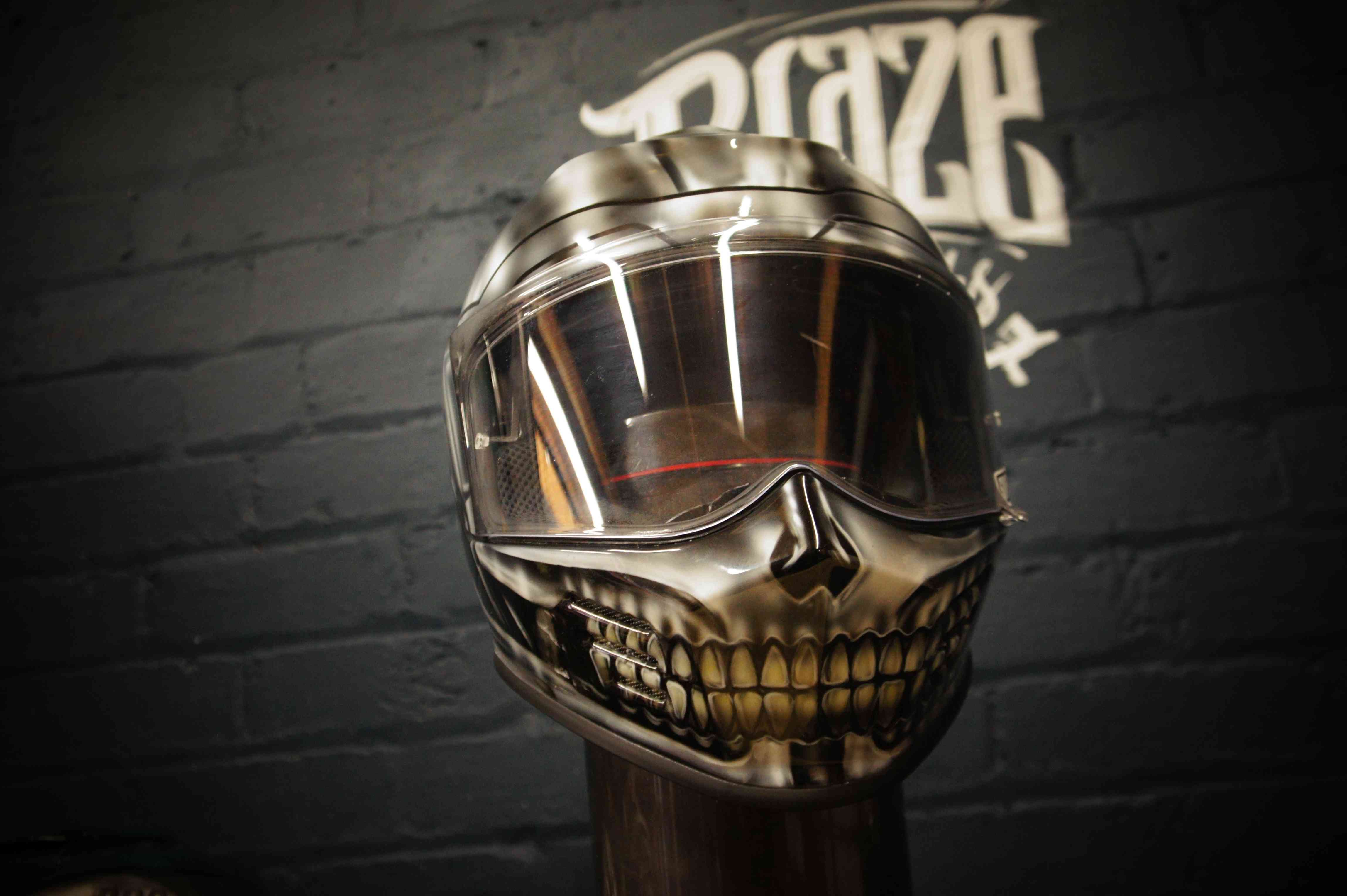 Chrome silver motorcycle helmet with realistic skull jaw design, metallic finish, clear visor, death head airbrushed artwork