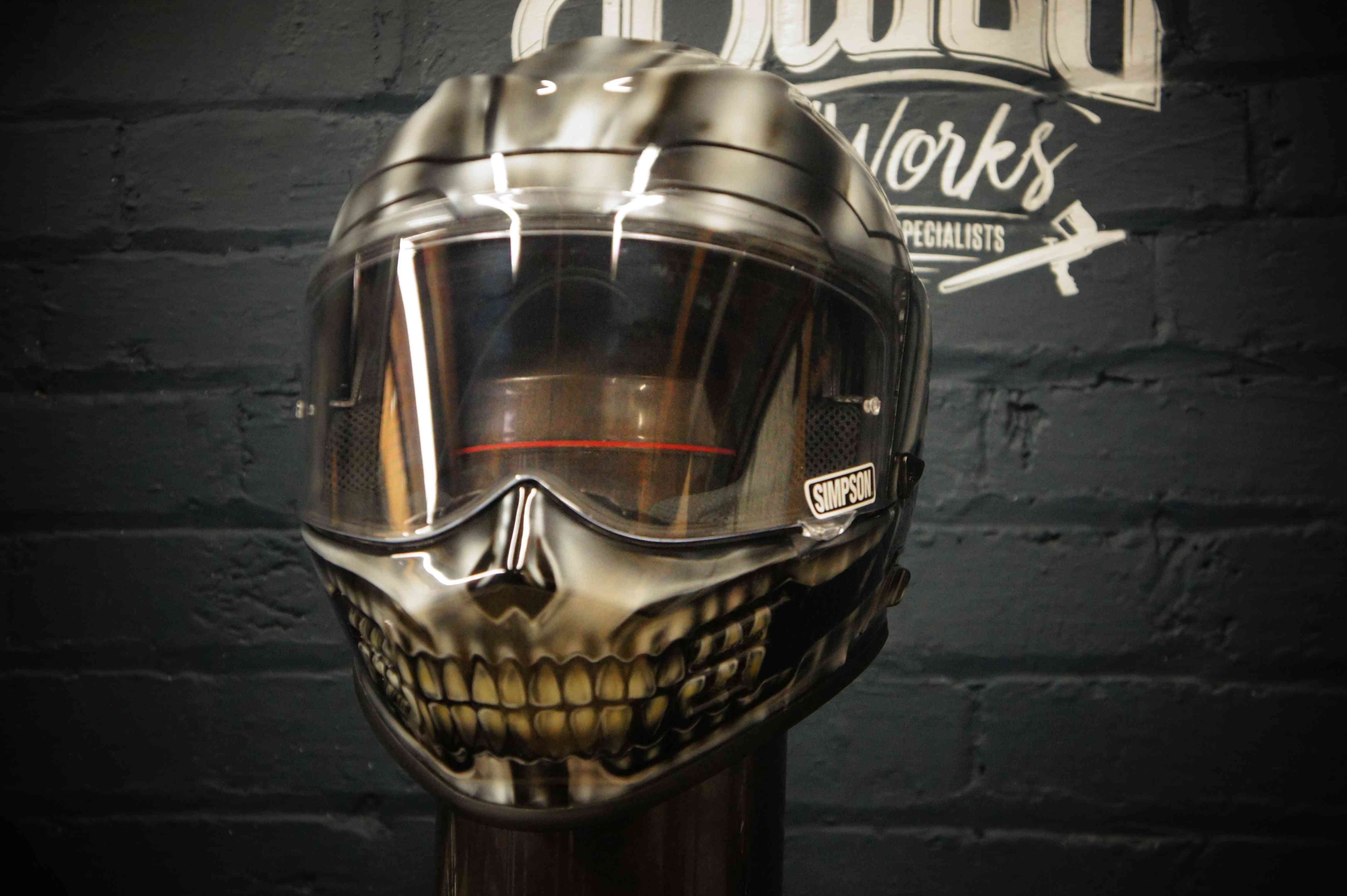 Metallic chrome motorcycle helmet with realistic gothic skull teeth and jaw design painted on lower face area in golden tones