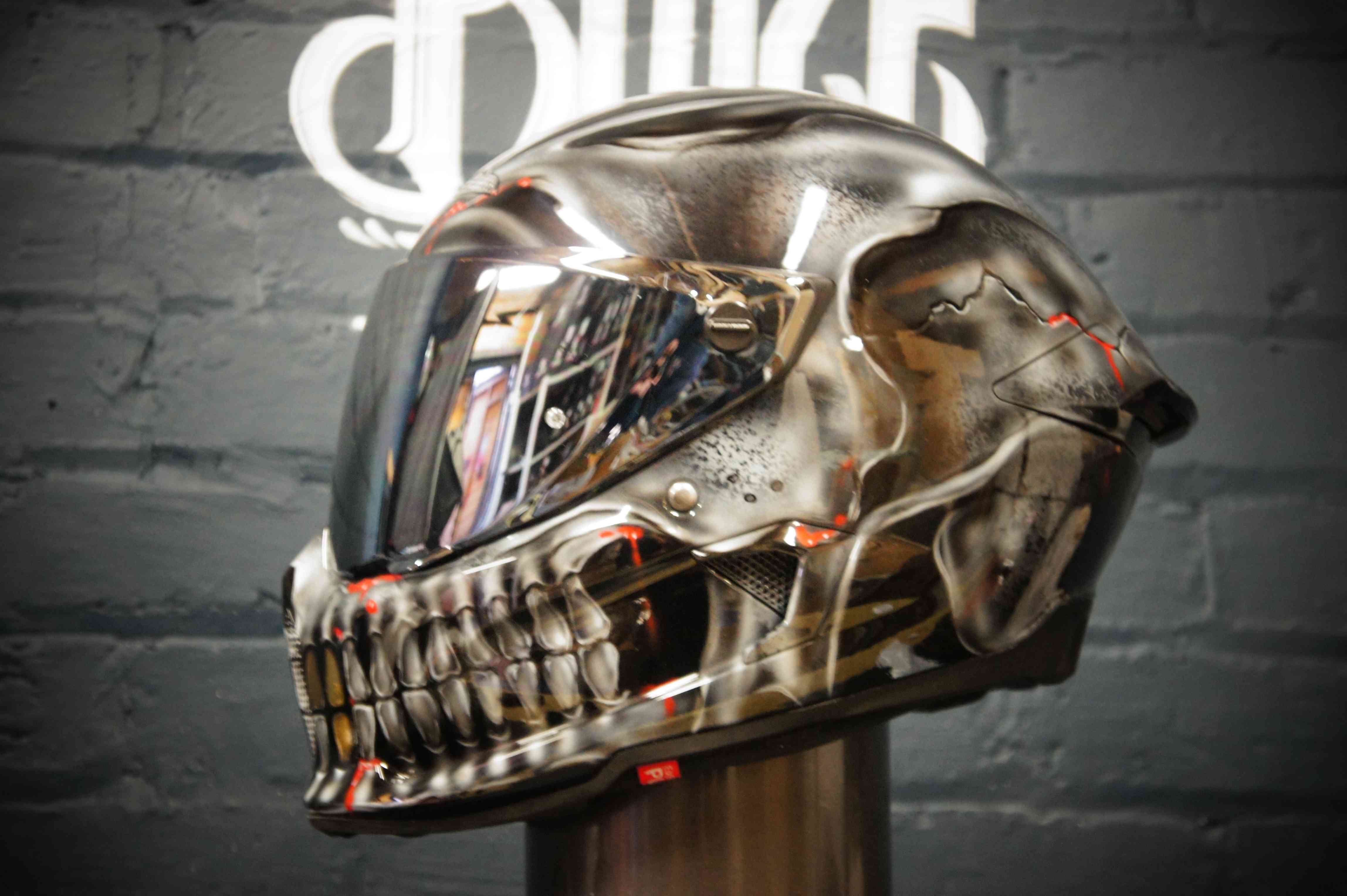 Chrome finish motorcycle helmet with hyper-realistic metallic skull design featuring detailed jaw and teeth in silver tones