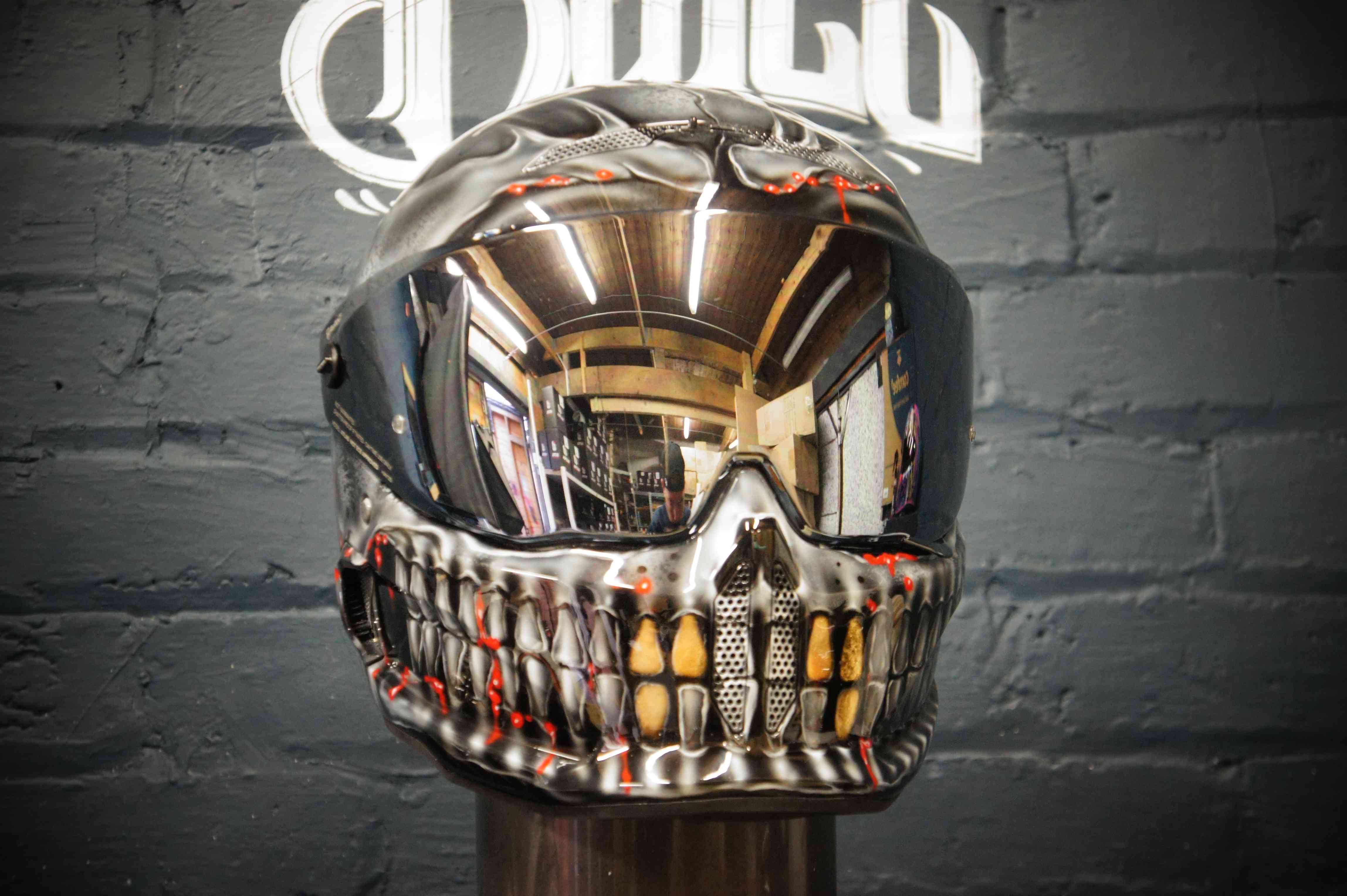 Motorcycle helmet with detailed skull and skeletal jaw design painted in silver and gold, featuring realistic teeth detail