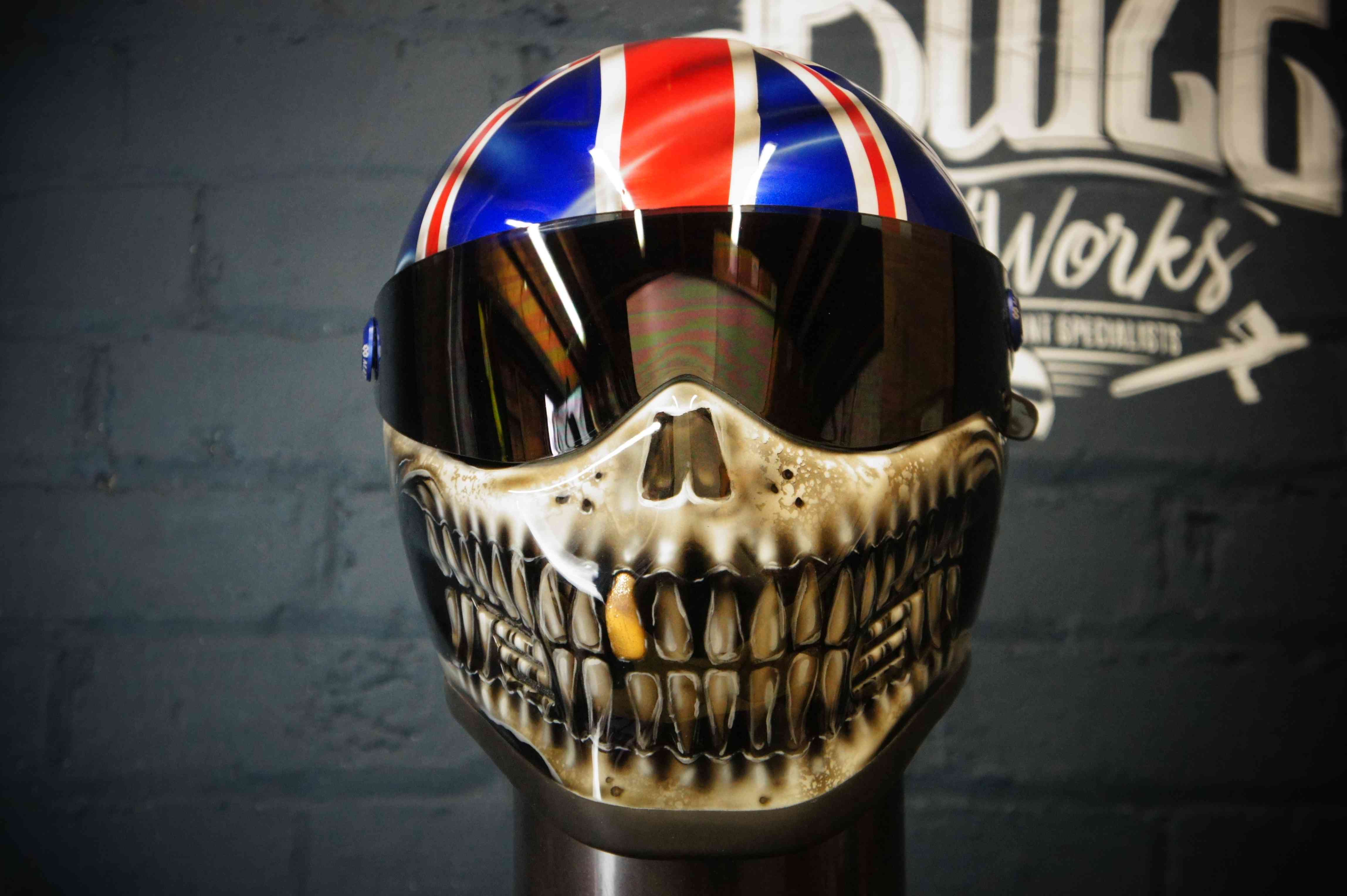 Union Jack motorcycle helmet with detailed skull and teeth airbrush design, British flag top, realistic bone jaw artwork
