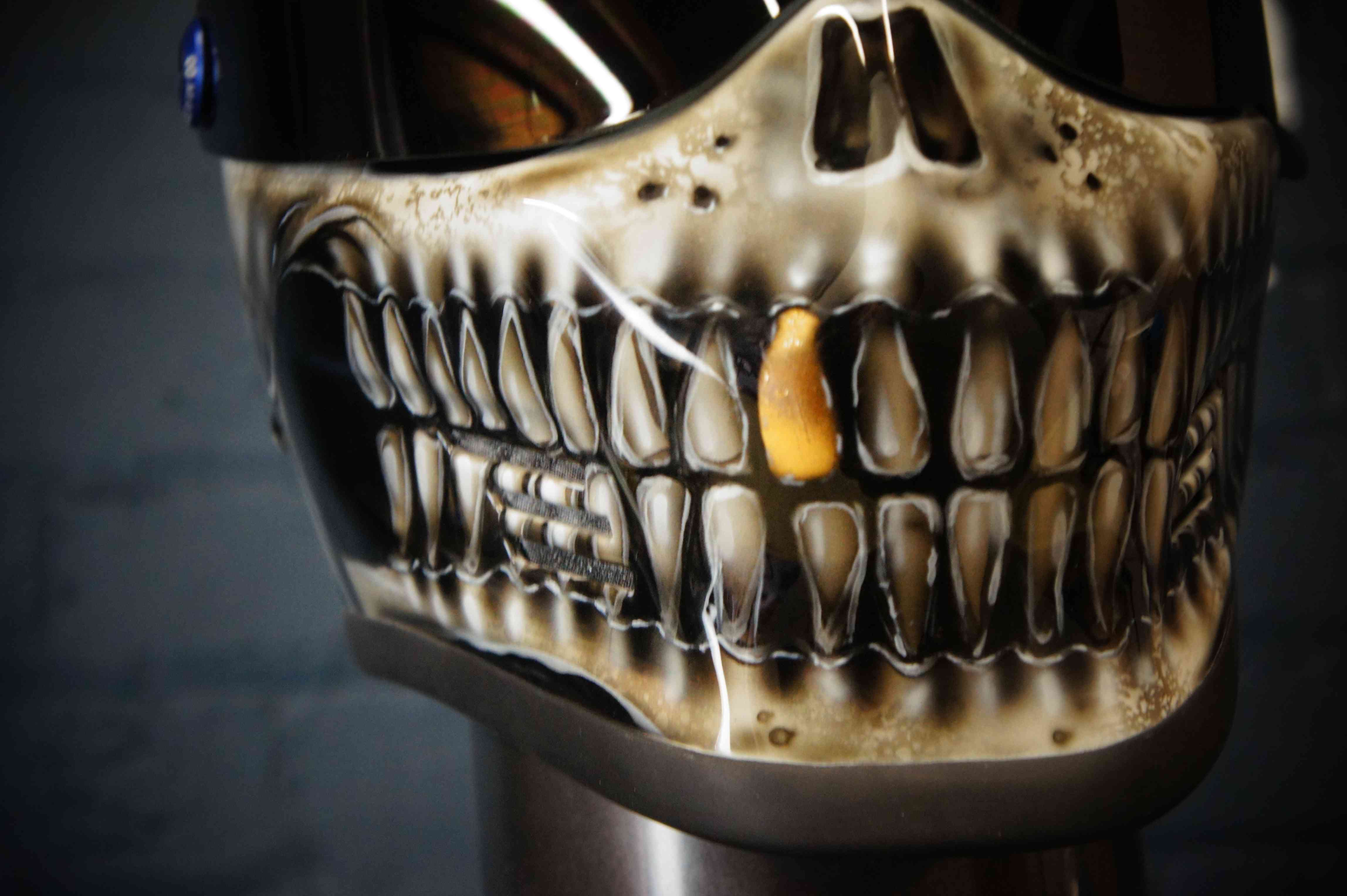 Photorealistic skull motorcycle helmet with anatomical jaw detail, cream bone coloring, and distinctive golden tooth accent