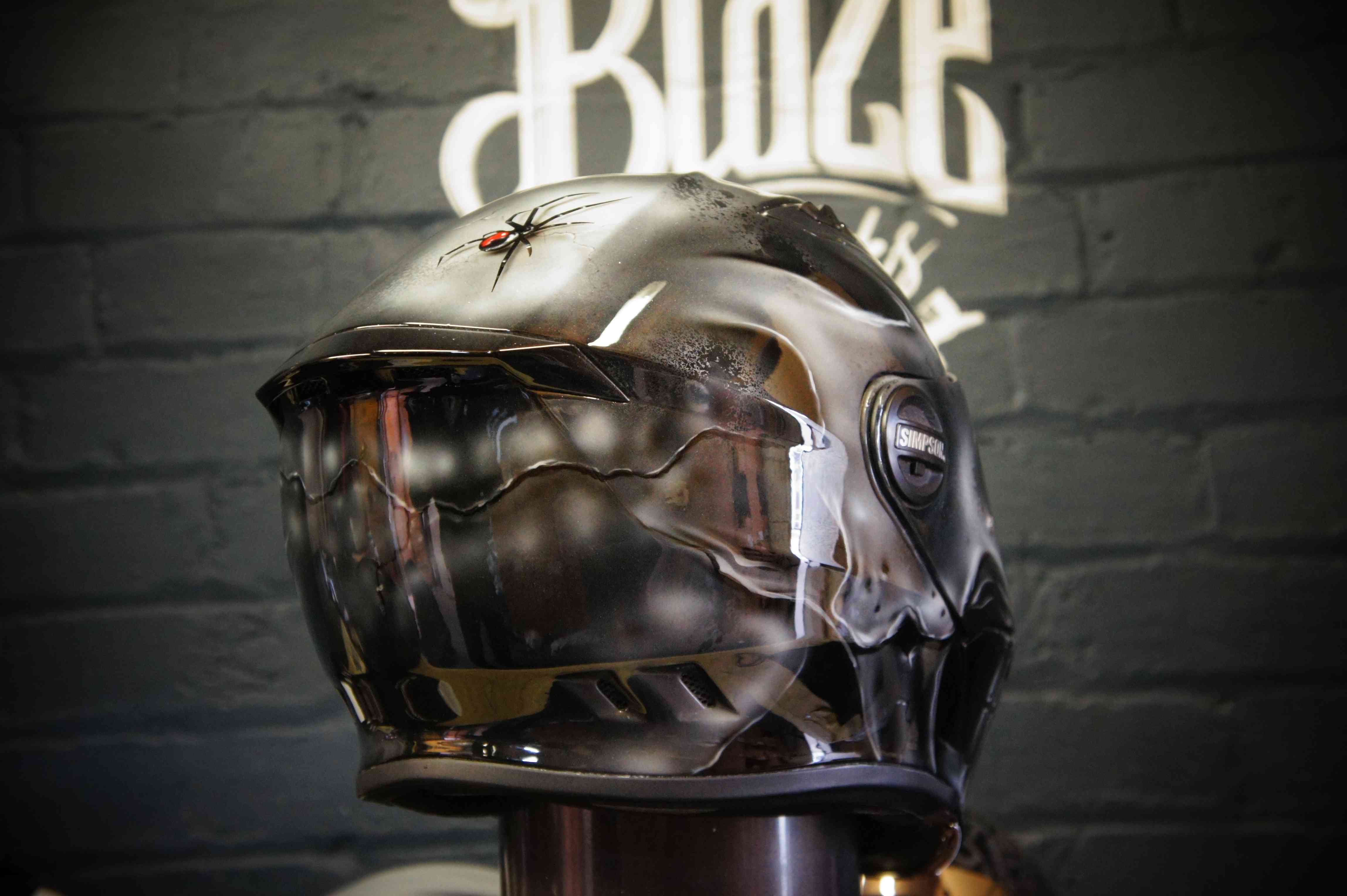 Dark metallic motorcycle helmet with realistic airbrushed skull design featuring anatomical details and gothic artwork