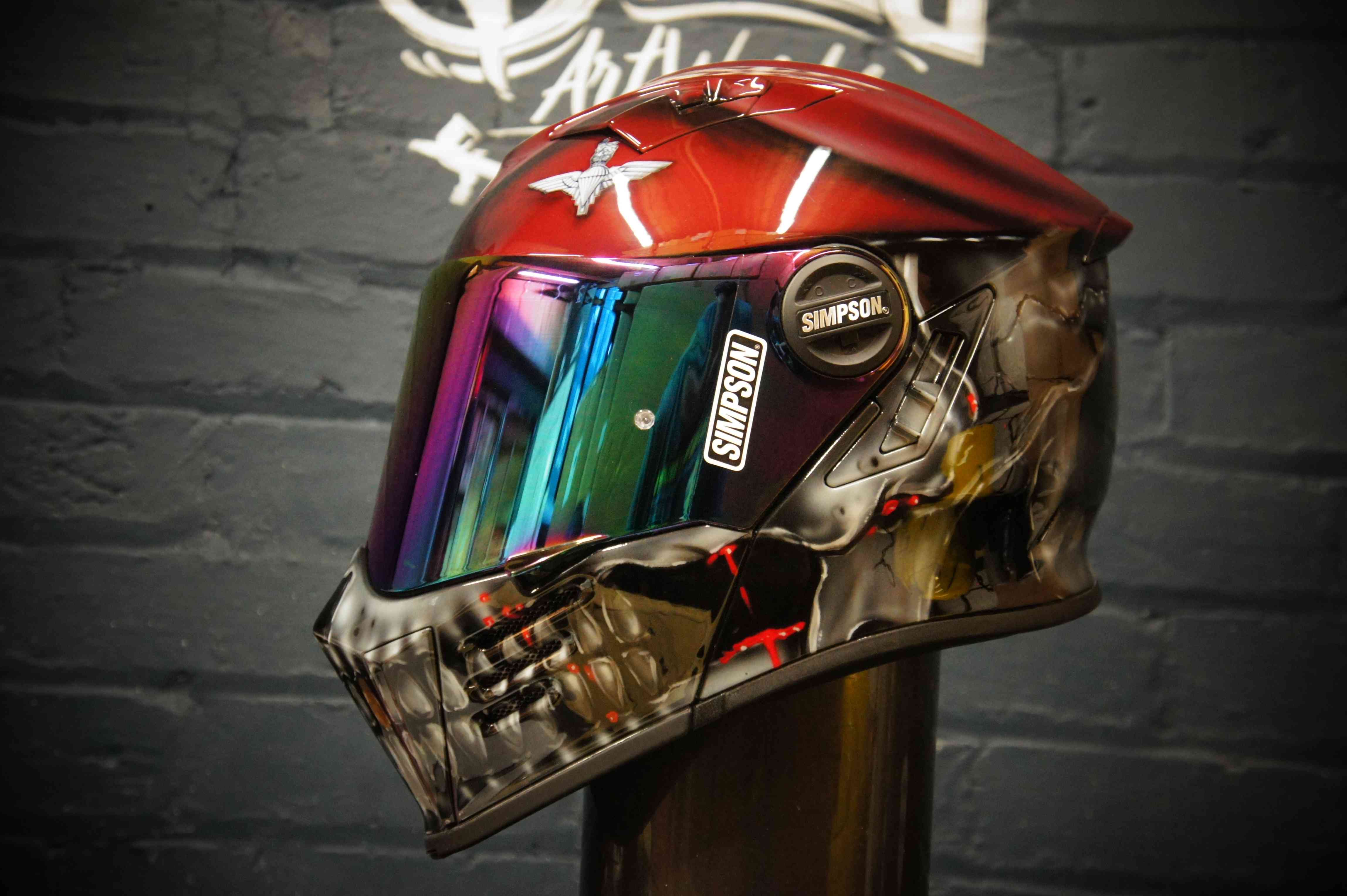 Red and black motorcycle helmet with detailed chrome skull jaw design and rainbow mirrored visor showing Gothic horror artwork