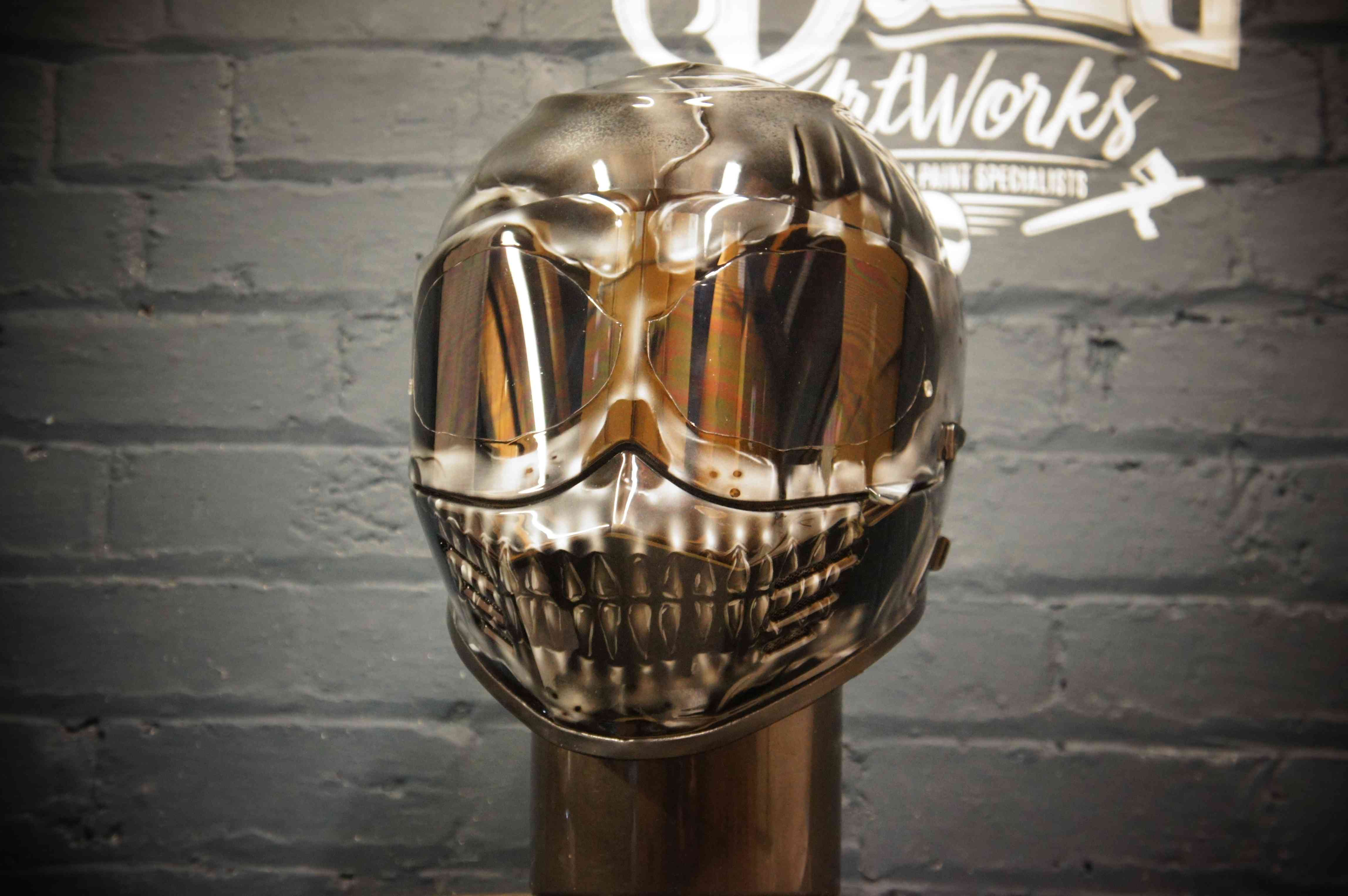 Metallic chrome skull helmet with mirror finish showing anatomical skull design, reflective eye sockets and detailed teeth