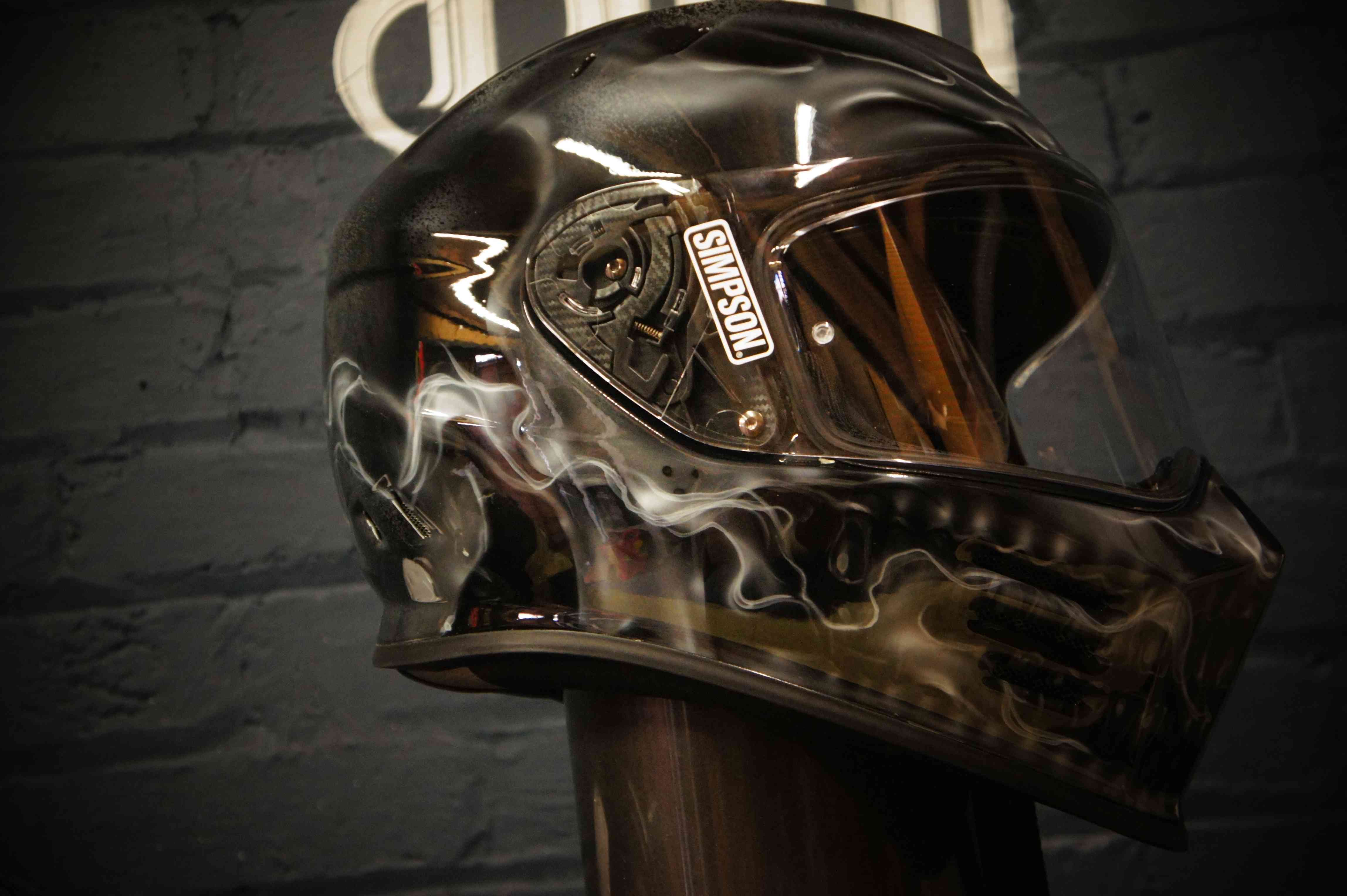 Black motorcycle helmet with realistic skull and smoke design, featuring detailed bone structure and wisping smoke effects
