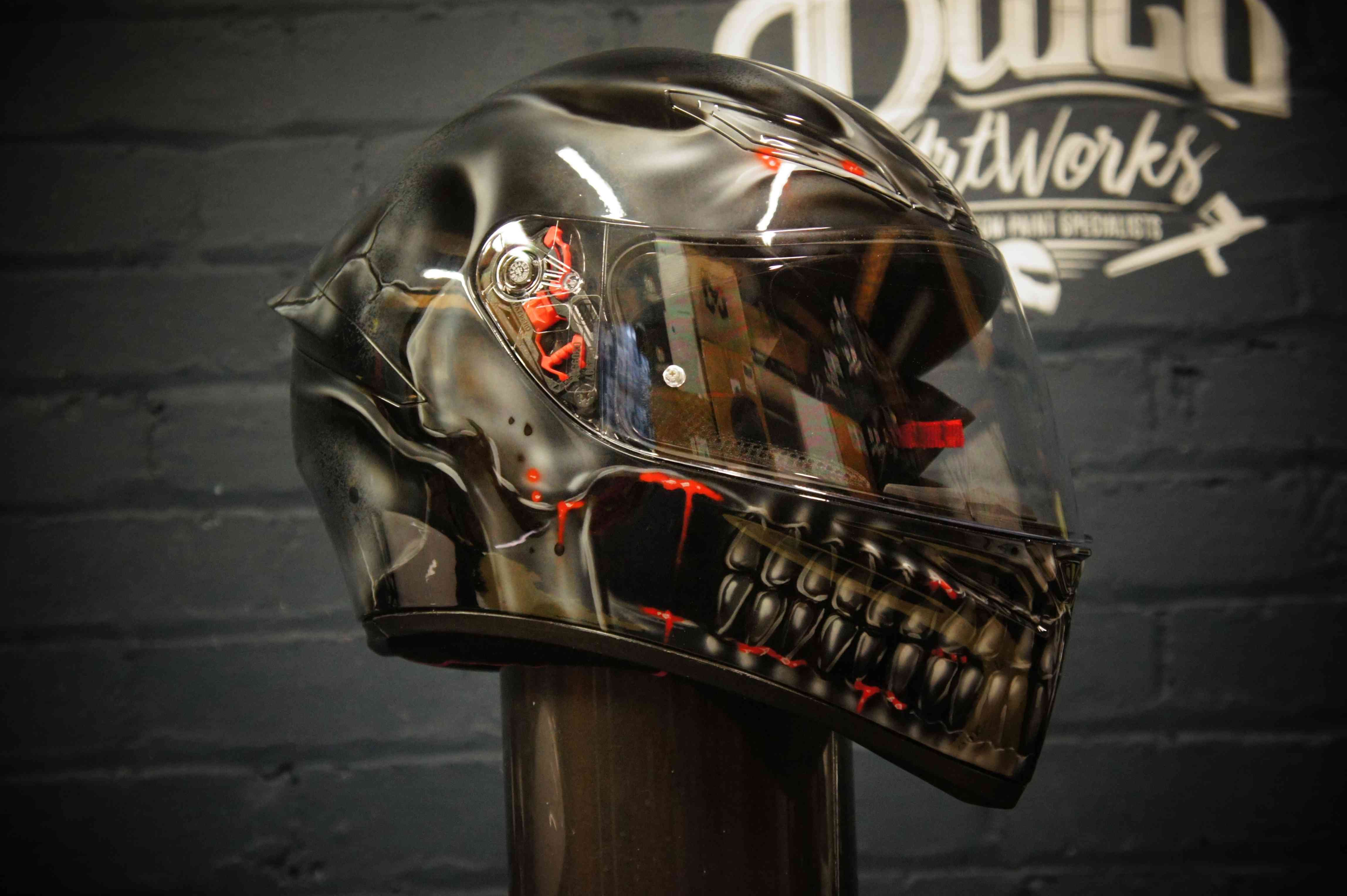 Black glossy motorcycle helmet with realistic skull design featuring exposed teeth, jaw structure and glowing red LED accents