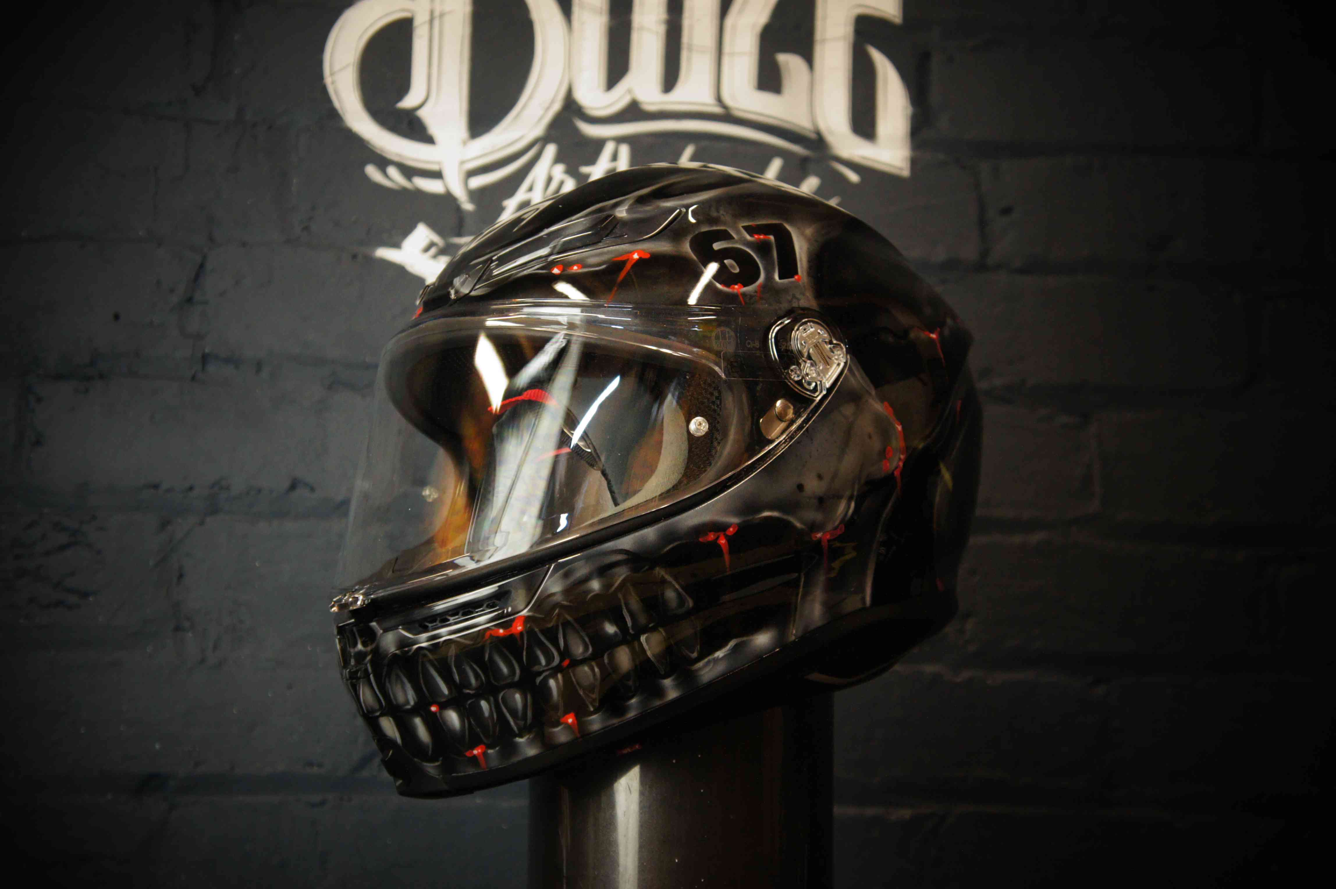 Black motorcycle helmet with realistic skull jaw design featuring exposed teeth, red glowing accents and dark horror-themed airbrush artwork