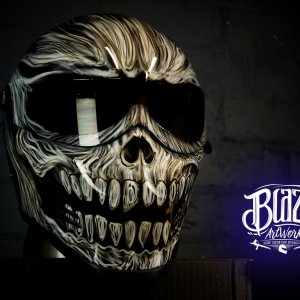 Gothic skull design motorcycle helmet with menacing fanged skull airbrush artwork in bone and black tones on dark background