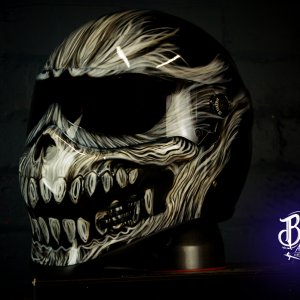 Motorcycle helmet with intricate carved bone skull design featuring flowing cream and brown carved patterns with menacing teeth