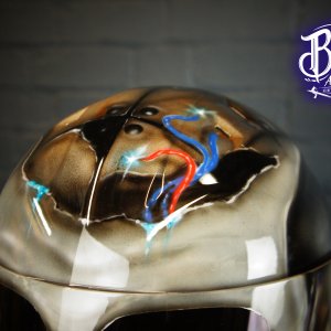 Chrome metallic motorcycle helmet with highly detailed airbrushed skull design featuring realistic bone structure in browns and blacks with blue and red accents