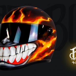 Motorcycle helmet with fiery orange flame paint and menacing white fanged teeth design on black background with mirrored visor