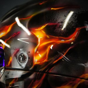 Black motorcycle helmet with realistic orange and red flames airbrushed across surface, dramatic fire effect artwork