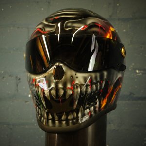Black motorcycle helmet with realistic flaming skull design featuring orange red flames yellow accents and detailed skeleton jaw artwork