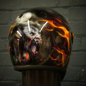 Black motorcycle helmet with demonic wolf creature surrounded by orange flames and red blood effects, professional airbrush art