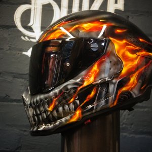 Black motorcycle helmet with realistic orange flame design and metallic skull graphic, featuring detailed airbrush work