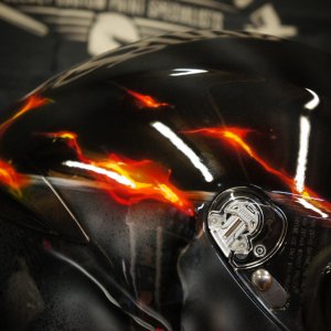 Black motorcycle helmet with realistic orange and red flames airbrushed across surface, creating dramatic fire effect