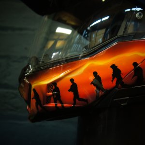 Motorcycle helmet with vibrant orange and yellow flame design airbrushed across black base, realistic fire effect paint job