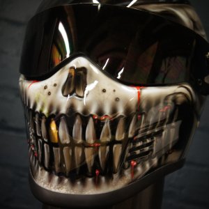 White skull jaw design with bared teeth and red blood effects painted on motorcycle helmet with reflective visor