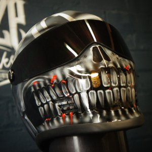 Chrome metallic skull motorcycle helmet with glossy black visor, red LED accents, detailed teeth and jaw structure