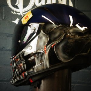 Black motorcycle helmet with detailed metallic skull design featuring anatomical jaw structure and red accents in photorealistic style