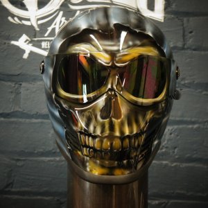 Reflective chrome skull motorcycle helmet with mirrored eye sockets displaying golden tinted reflection and detailed jaw structure