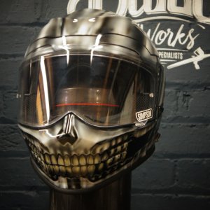 Metallic chrome motorcycle helmet with realistic gothic skull teeth and jaw design painted on lower face area in golden tones