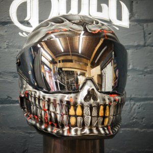 Motorcycle helmet with detailed skull and skeletal jaw design painted in silver and gold, featuring realistic teeth detail