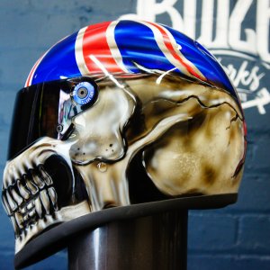 Custom painted motorcycle helmet featuring photorealistic metallic gold skull design with Union Jack pattern on blue background