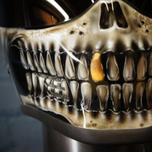 Photorealistic skull motorcycle helmet with anatomical jaw detail, cream bone coloring, and distinctive golden tooth accent
