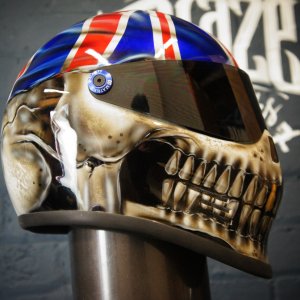 Realistic skull motorcycle helmet with Union Jack flag design on top, detailed anatomical features, metallic finish, visor