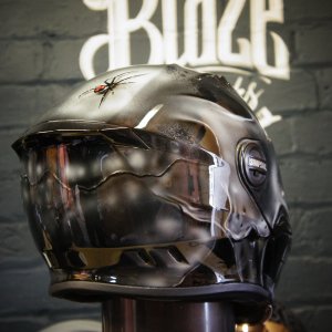 Dark metallic motorcycle helmet with realistic airbrushed skull design featuring anatomical details and gothic artwork