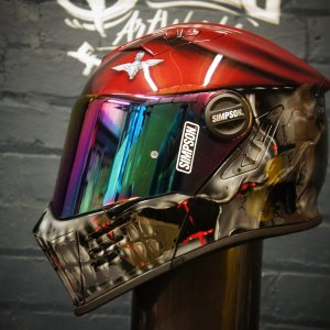 Red and black motorcycle helmet with detailed chrome skull jaw design and rainbow mirrored visor showing Gothic horror artwork