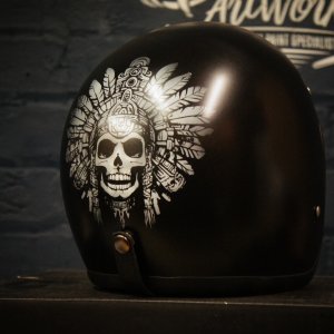Black motorcycle helmet with detailed white skull wearing elaborate Aztec feathered headdress artwork airbrushed on side