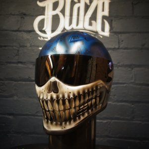 Blue metallic skull motorcycle helmet with realistic bone jaw airbrush art, golden teeth detail on dark background