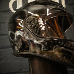 Black motorcycle helmet with realistic skull and smoke design, featuring detailed bone structure and wisping smoke effects