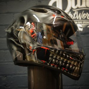 Black glossy motorcycle helmet with realistic skull design featuring exposed teeth, jaw structure and glowing red LED accents