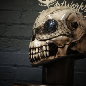Cream colored motorcycle helmet with airbrushed skeletal skull design featuring mesh goggle effect and exposed jaw teeth
